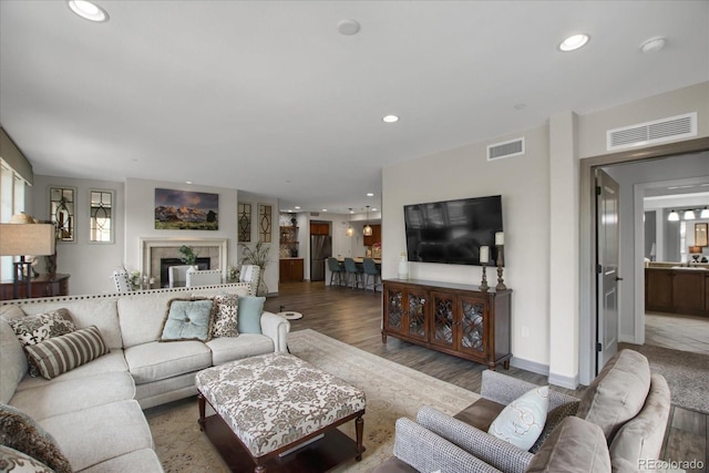 living area with recessed lighting, visible vents, and wood finished floors