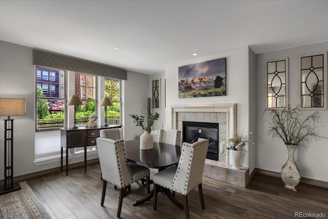 dining space featuring baseboards, a tile fireplace, recessed lighting, and wood finished floors