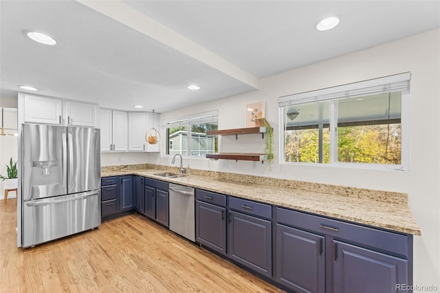 kitchen featuring light hardwood / wood-style flooring, sink, white cabinetry, blue cabinetry, and appliances with stainless steel finishes