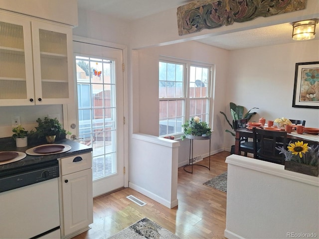 kitchen with white dishwasher, light hardwood / wood-style flooring, and white cabinets