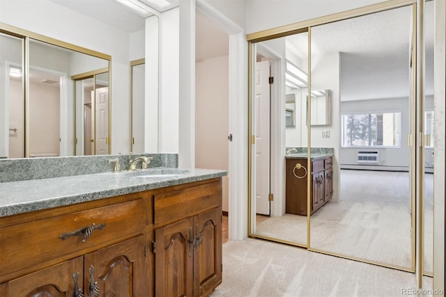 bathroom featuring a wall mounted AC, a textured ceiling, vanity, and baseboard heating