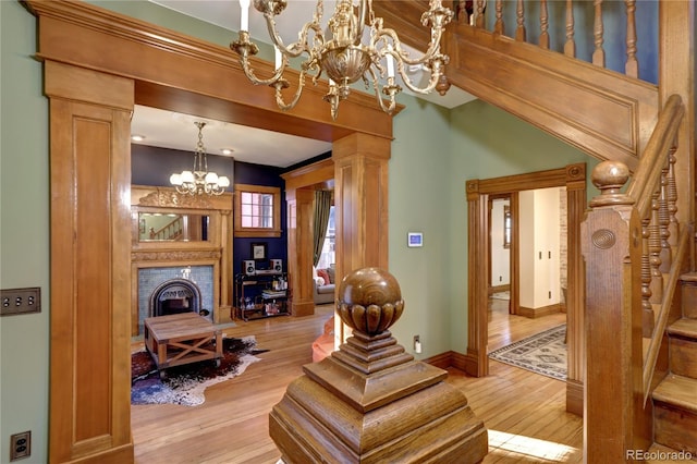 interior space with decorative columns, light hardwood / wood-style floors, a notable chandelier, and a brick fireplace