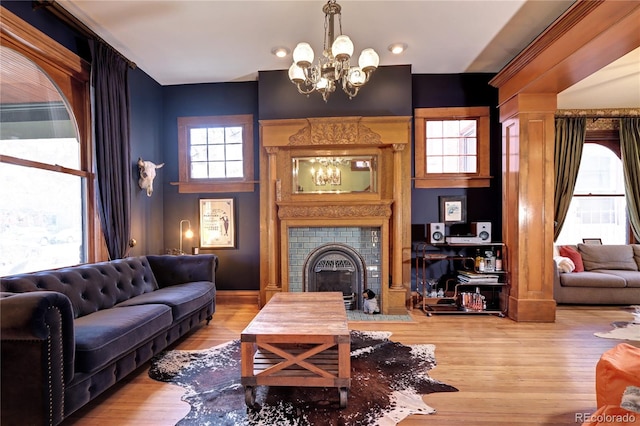 living room with a tiled fireplace, a chandelier, and wood-type flooring