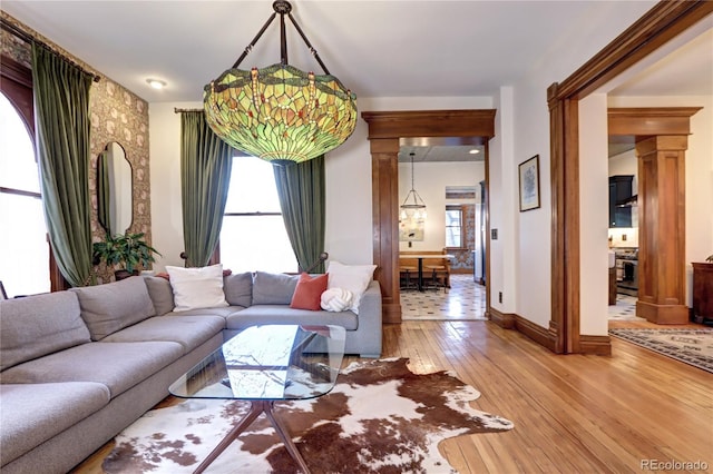 living room with decorative columns, plenty of natural light, and wood-type flooring