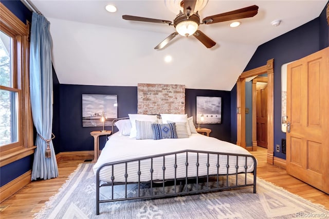 bedroom with multiple windows, light hardwood / wood-style flooring, ceiling fan, and lofted ceiling