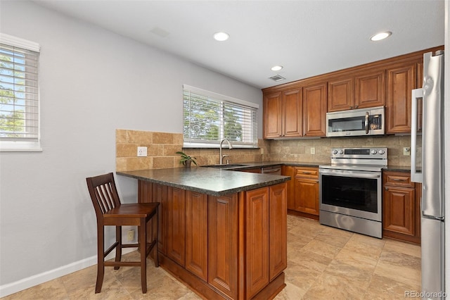 2366 S Troy St, Aurora, CO 80014 - kitchen with stainless steel appliances, a peninsula, dark countertops, brown cabinets, and recessed lighting