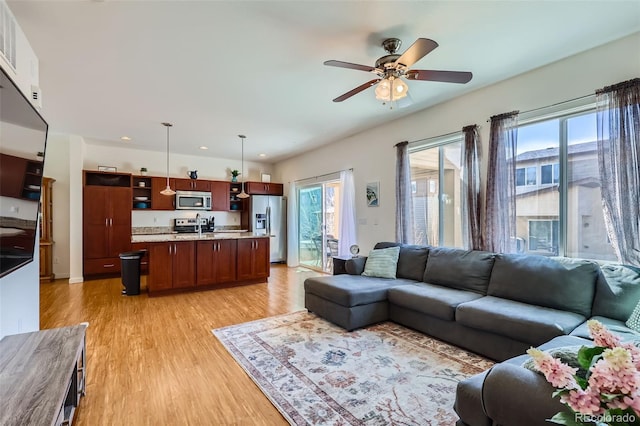 living area with light wood-type flooring and ceiling fan