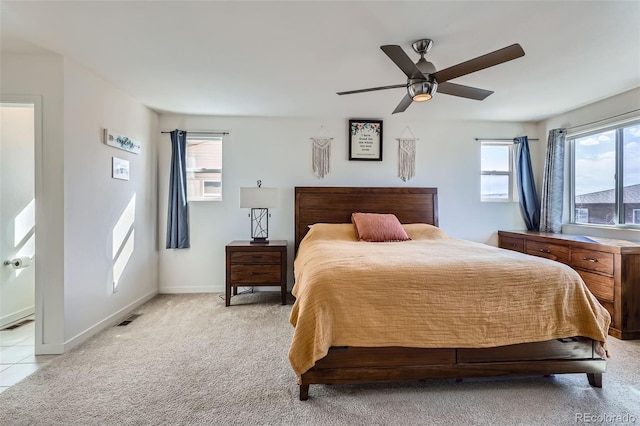 bedroom featuring a ceiling fan, visible vents, light colored carpet, and baseboards