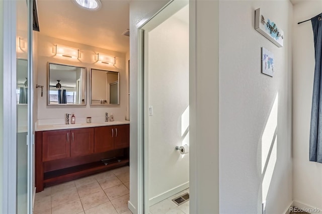 bathroom featuring baseboards, visible vents, double vanity, a sink, and tile patterned floors