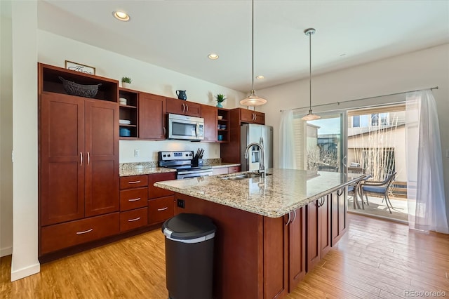 kitchen with a sink, open shelves, light wood-type flooring, stainless steel appliances, and a kitchen island with sink