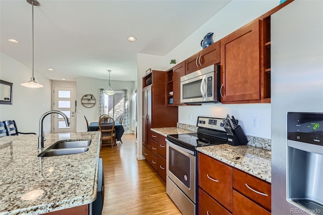 kitchen featuring a sink, light wood-style flooring, appliances with stainless steel finishes, hanging light fixtures, and open shelves