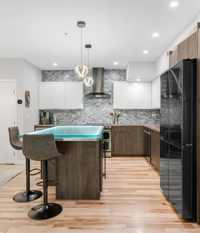 kitchen featuring a kitchen breakfast bar, backsplash, modern cabinets, stainless steel appliances, and wall chimney exhaust hood