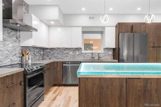 kitchen featuring wall chimney range hood, white cabinets, appliances with stainless steel finishes, visible vents, and modern cabinets