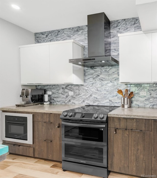 kitchen with light countertops, white cabinets, double oven range, and wall chimney exhaust hood