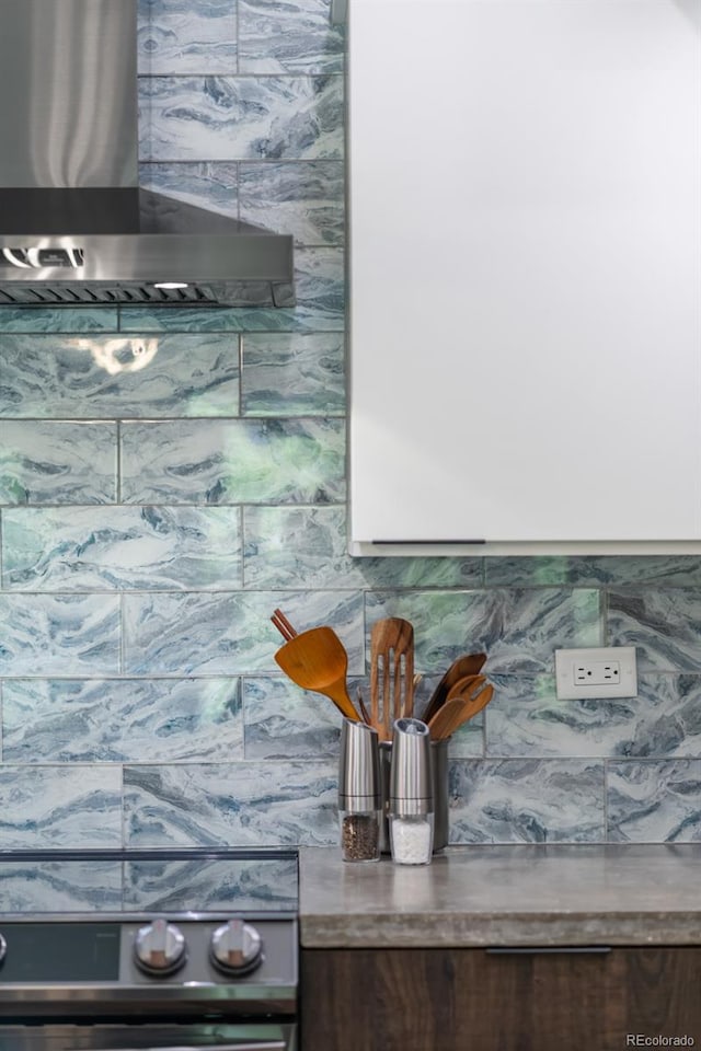 interior details with wall chimney range hood, tasteful backsplash, and range
