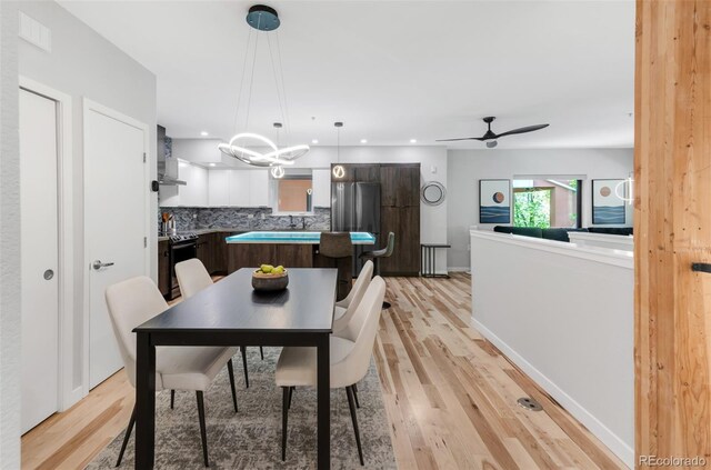 dining room featuring light wood-style floors, recessed lighting, and ceiling fan with notable chandelier