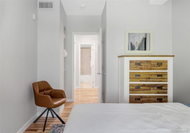 bedroom featuring baseboards, visible vents, and wood finished floors