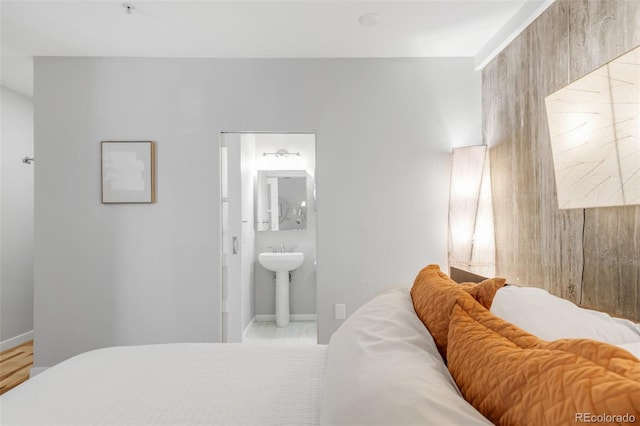 bedroom with a sink, baseboards, and ensuite bath