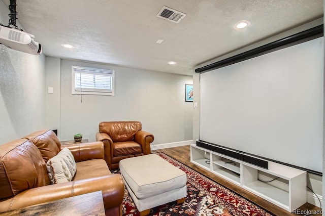 cinema room with hardwood / wood-style floors and a textured ceiling