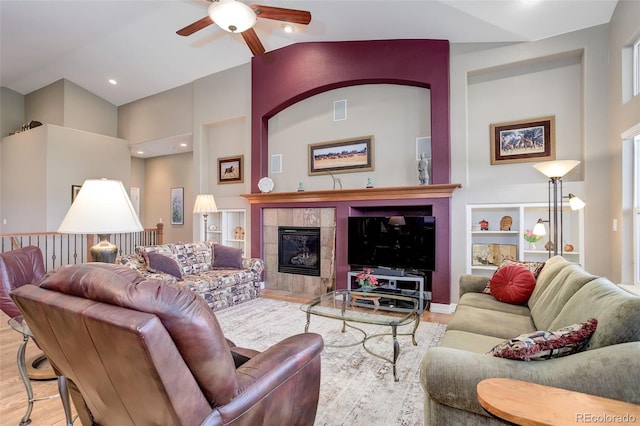 14879 Xenia St, Thornton, CO 80602 - living room featuring wood finished floors, ceiling fan, a tiled fireplace, high vaulted ceiling, and built in features