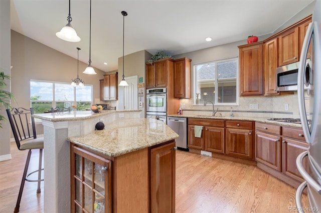 14879 Xenia St, Thornton, CO 80602 - kitchen featuring stainless steel appliances, a sink, lofted ceiling, light wood-style floors, and brown cabinets