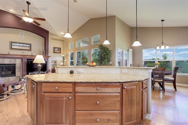 14879 Xenia St, Thornton, CO 80602 - kitchen with a tile fireplace, light wood-type flooring, light stone countertops, ceiling fan, and high vaulted ceiling