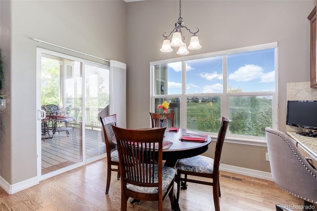 14879 Xenia St, Thornton, CO 80602 - dining space featuring a chandelier, baseboards, light wood-style flooring, and a towering ceiling