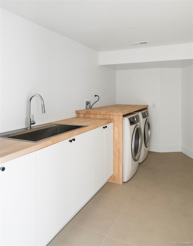 laundry area with cabinets, sink, washer and dryer, and light tile patterned floors