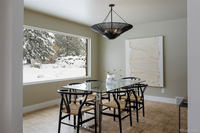 dining space featuring parquet flooring and a notable chandelier