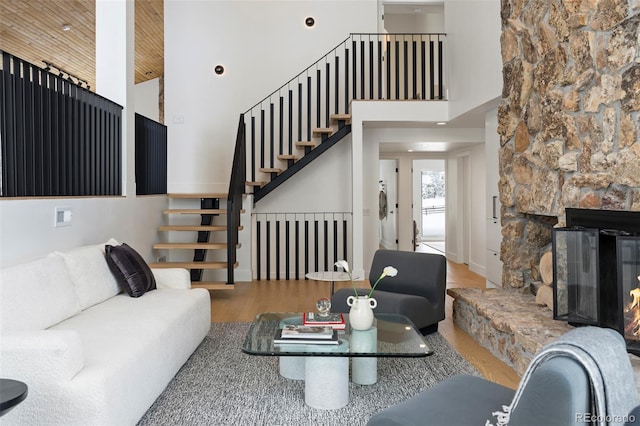 living room featuring hardwood / wood-style flooring, a stone fireplace, and high vaulted ceiling