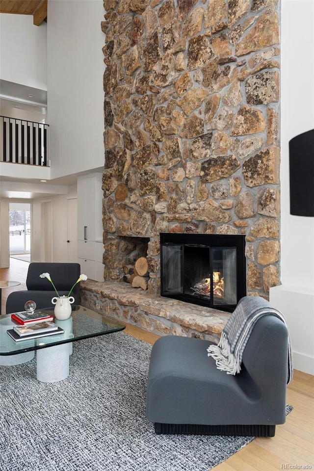 living room featuring high vaulted ceiling, beam ceiling, hardwood / wood-style floors, and a fireplace