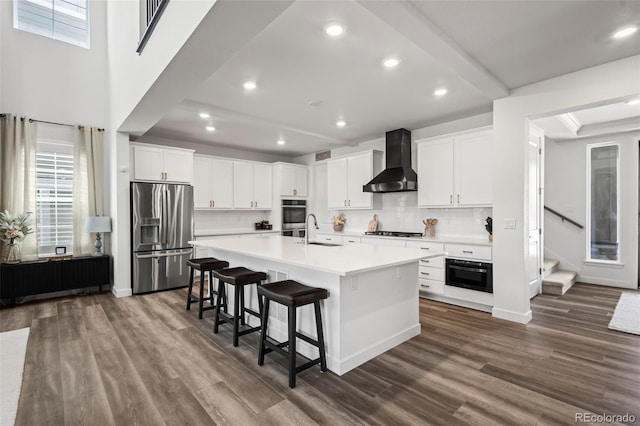 17121 Desert Wine Ln, Parker, CO 80134 - kitchen with stainless steel appliances, wall chimney exhaust hood, a sink, a center island with sink, and backsplash
