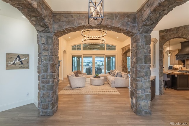 living room with hardwood / wood-style floors, an inviting chandelier, french doors, and vaulted ceiling