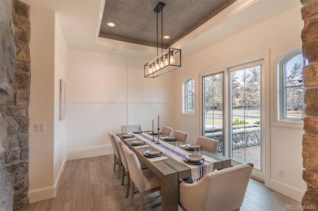 dining room with crown molding, light hardwood / wood-style floors, and a tray ceiling