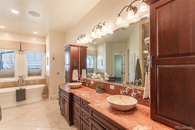 bathroom with a tub to relax in, tile patterned floors, and vanity