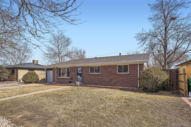 ranch-style house featuring a garage, brick siding, fence, and a front lawn