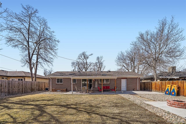 view of front facade with brick siding, a front lawn, a patio area, and a fenced backyard