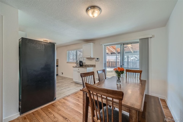 dining space featuring a textured ceiling, light wood-type flooring, and baseboards