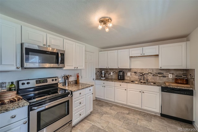 kitchen with stainless steel appliances, a sink, white cabinetry, and decorative backsplash