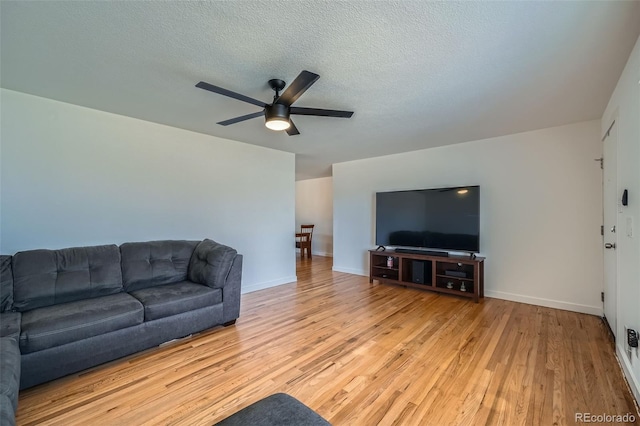 living room featuring light wood-style floors, baseboards, and a textured ceiling