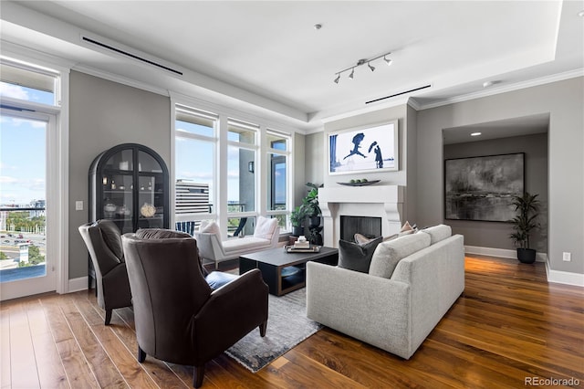 living room featuring dark hardwood / wood-style flooring, track lighting, and ornamental molding