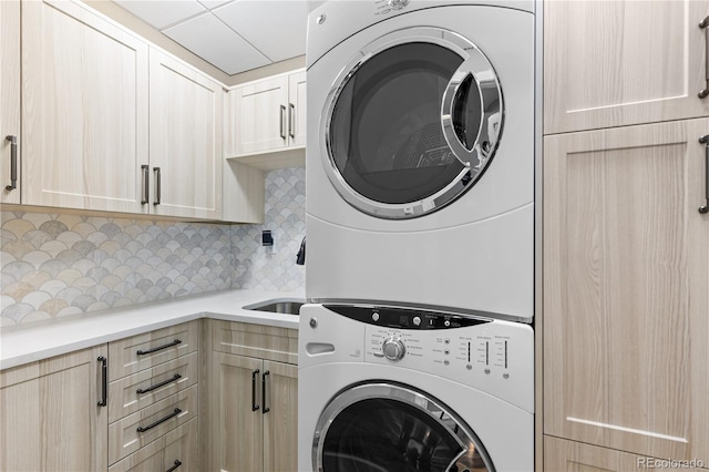 laundry area featuring cabinets and stacked washer / drying machine