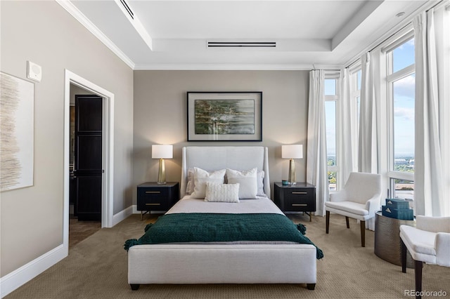 carpeted bedroom with a tray ceiling and ornamental molding