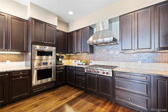 kitchen with backsplash, wall chimney exhaust hood, stainless steel appliances, and dark wood-type flooring