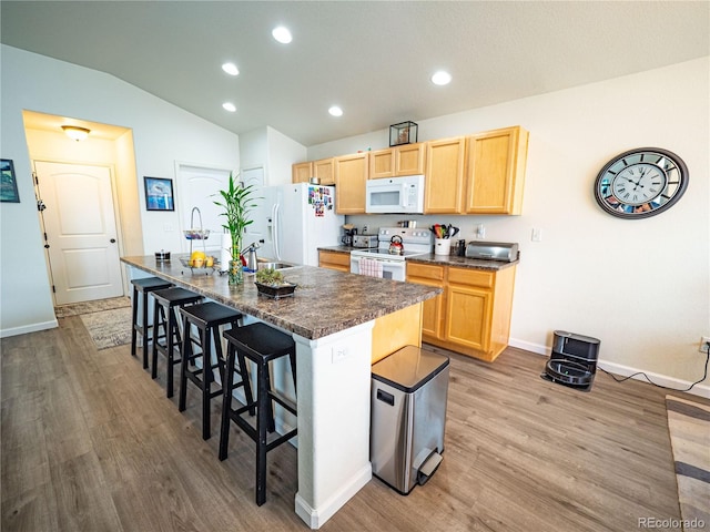 8809 15th Street Rd, Greeley, CO 80634 - kitchen featuring white appliances, light brown cabinetry, dark countertops, wood finished floors, and baseboards