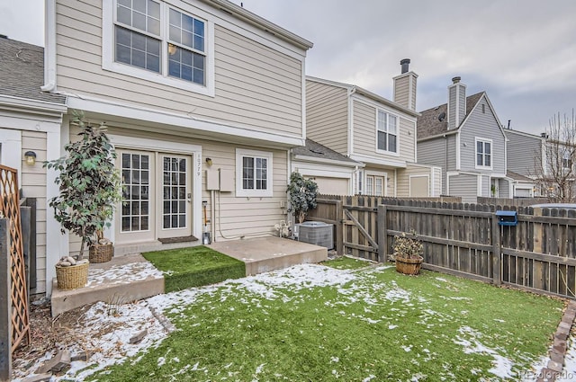 snow covered house featuring cooling unit, a patio area, and a lawn