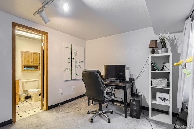 carpeted home office featuring track lighting