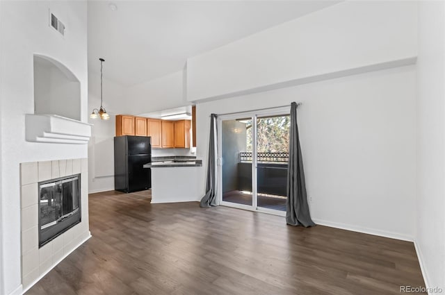 unfurnished living room featuring a wall mounted air conditioner, dark hardwood / wood-style floors, a tiled fireplace, and an inviting chandelier