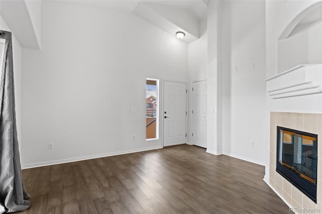 unfurnished living room with a towering ceiling, dark hardwood / wood-style floors, and a fireplace