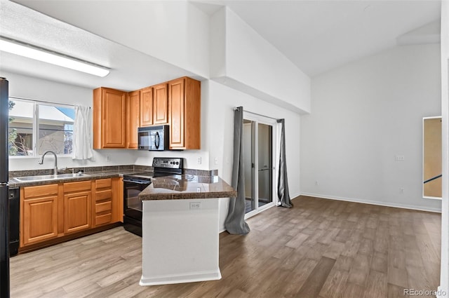 kitchen with sink, black appliances, lofted ceiling, and light hardwood / wood-style flooring